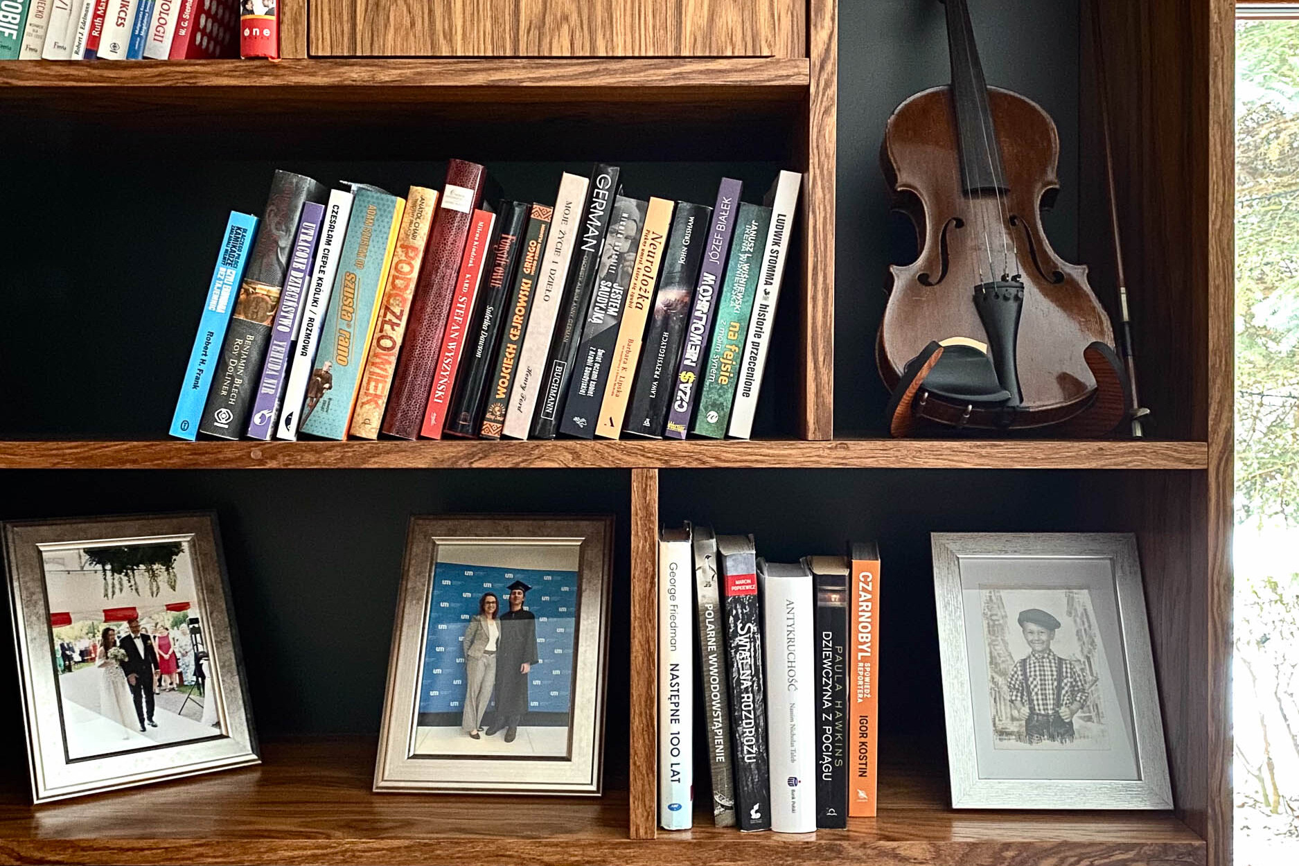przedmioty w biblioteczce: ramki ze zdjęciami, skrzypce i książki